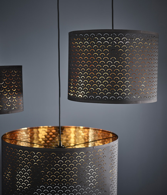 Pendant lamps with black perforated metal shades and golden inner finish, casting a warm and decorative light.