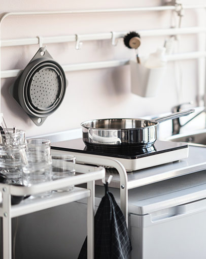 Clean kitchen setup with SUNNERSTA mini kitchen, LAGAN mixer tap and fridge, TILLREDA induction hob and IKEA 365+ sauté pan.