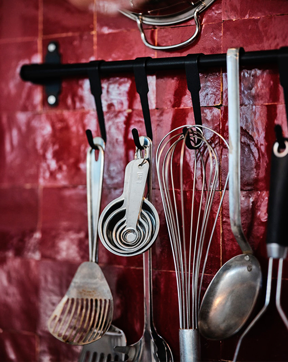 Organized kitchen wall with HULTARP rail and hooks, GRUNKA utensils, and VARDAGEN measuring spoons.