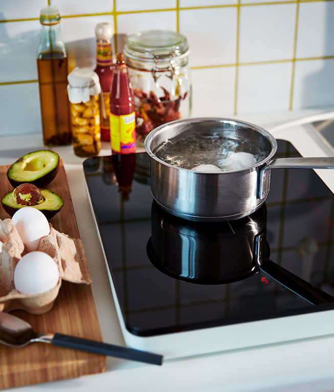 A HEMKOMST Saucepan on an induction stove next to Korken jars with lids