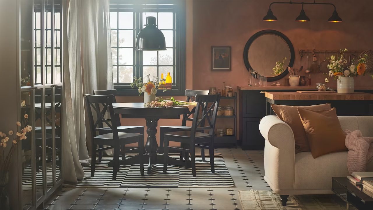 Una sala de estar y comedor de tonos neutros con sofá beige, mesa redonda oscura y una combinación de alfombras a rayas y lisas.