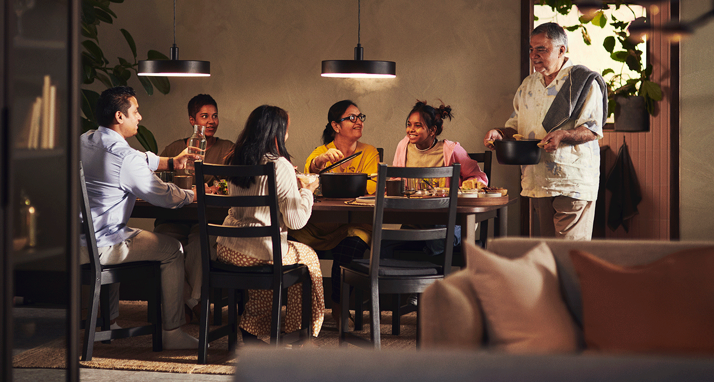 Multigenerational family sharing a meal around the table in a warm, cozy dining room.