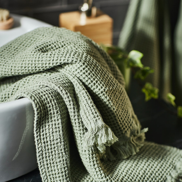 Un lavamanos TÖRNVIKEN con una toalla de baño verde VALLASÅN.
