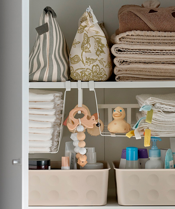 An open cabinet displays beige towels, diapers, and baby items organized in baskets. Clean and functional atmosphere.