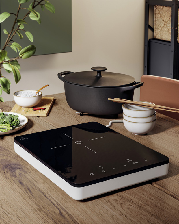  Modern kitchen with black induction cooktop, large pot, and various cooking ingredients on a wooden table.