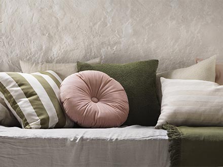Sofá decorado con cojines de varios colores y texturas contra una pared texturizada.