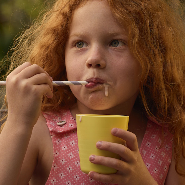 niña pelirroja comiendo en un vaso amarillo