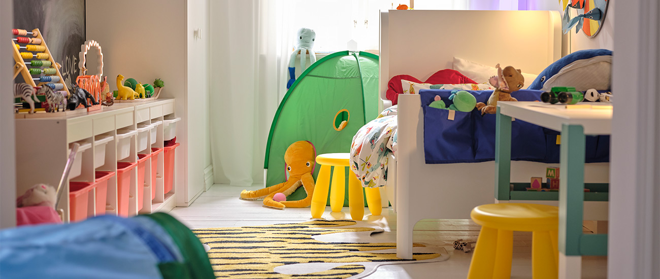 Habitación infantil colorida con juguetes, cama, mesa y tienda de niño.