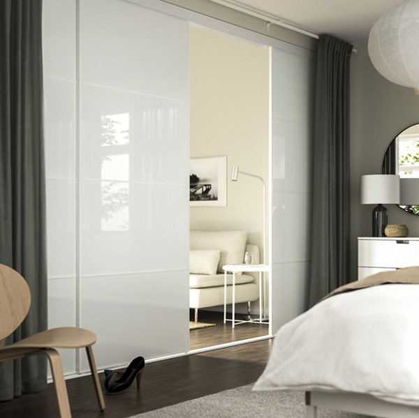 Modern, serene bedroom with white gloss sliding door. Neutral tones, natural light, and minimalist decor create a calm space.