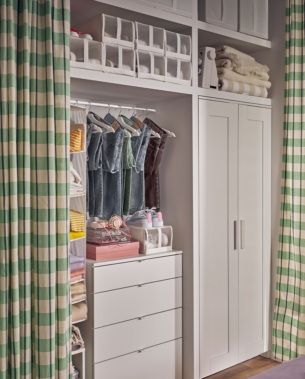 Armario del dormitorio, con accesorios para organizar la ropa del dormitorio, todo cubierto con una cortina de cuadros verdes.