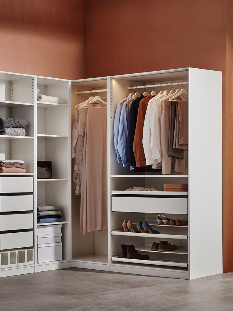  Armario esquinero blanco con ropa organizada, estantes y cajones, ambiente moderno y cálido.