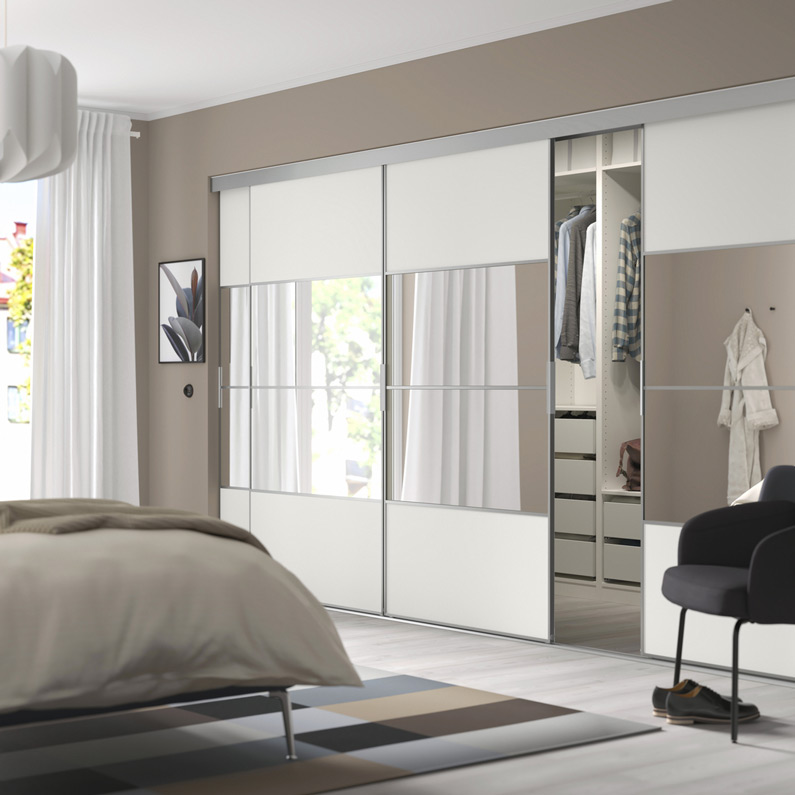 Modern bedroom with  sliding wardrobe featuring white panels and mirrored doors, offering ample storage.