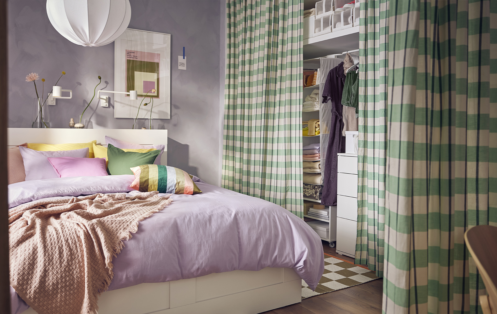 Dormitorio colorido, una cama grande con cojines de colores vivos, una funda de color morado claro y un armario con cuadros escoceses de color verde.