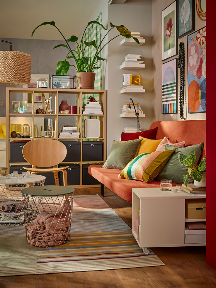 Colorful environment with a minimalist sofa with several multicolored cushions, 70's style, there is an open shelf of pine wood,