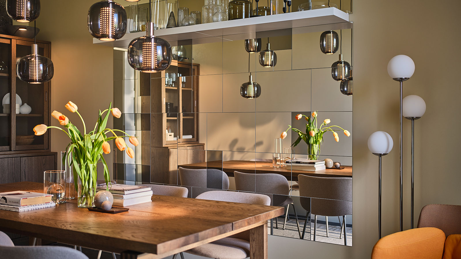 A dining room with personality, featuring mirrored walls, muted tones, dark wood, and elegant furniture