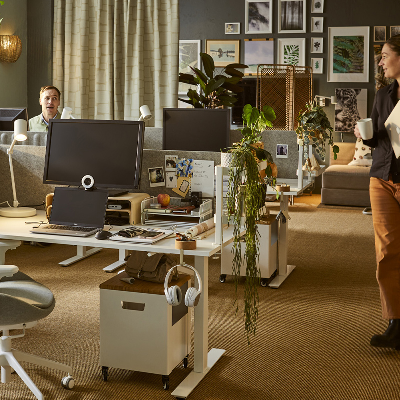 Warm office space with natural touches featuring TROTTEN desks, NYMÅNE lamps and VATTENKAR stands for a functional setup.