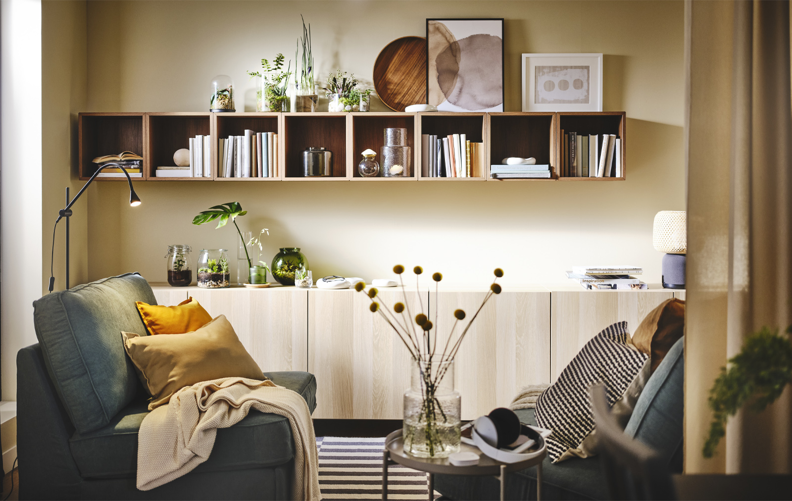 Modern style environment in pine wood, there is a gray armchair and has a mustard cushion and a blanket on top, there is a console cabinet, and wall shelves type box.