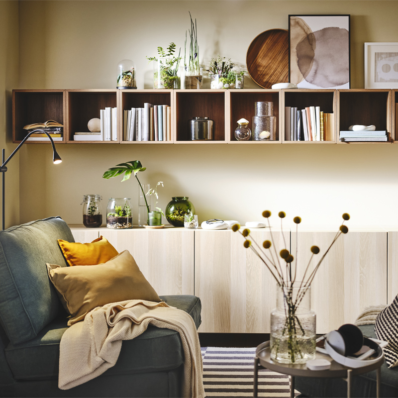 Modern style environment in pine wood, there is a gray armchair and has a mustard cushion and a blanket on top, there is a console cabinet, and wall shelves type box.