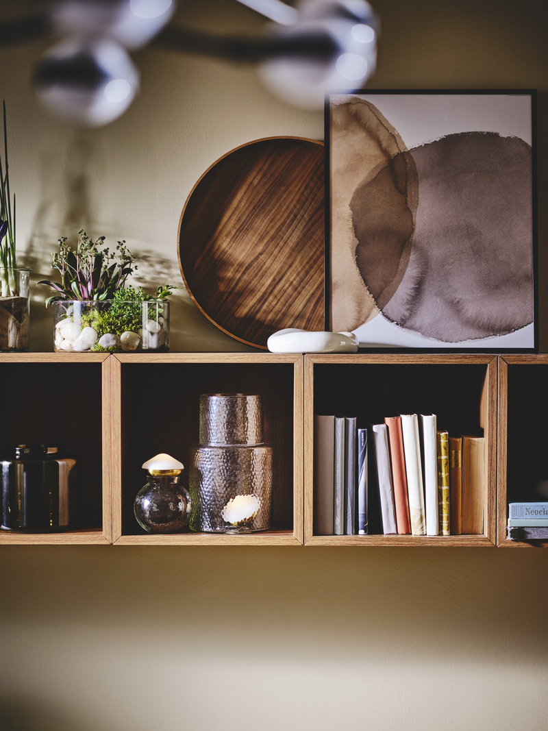 Estantería de pared, de estilo moderno en madera, con libros y jarrones como decoración.