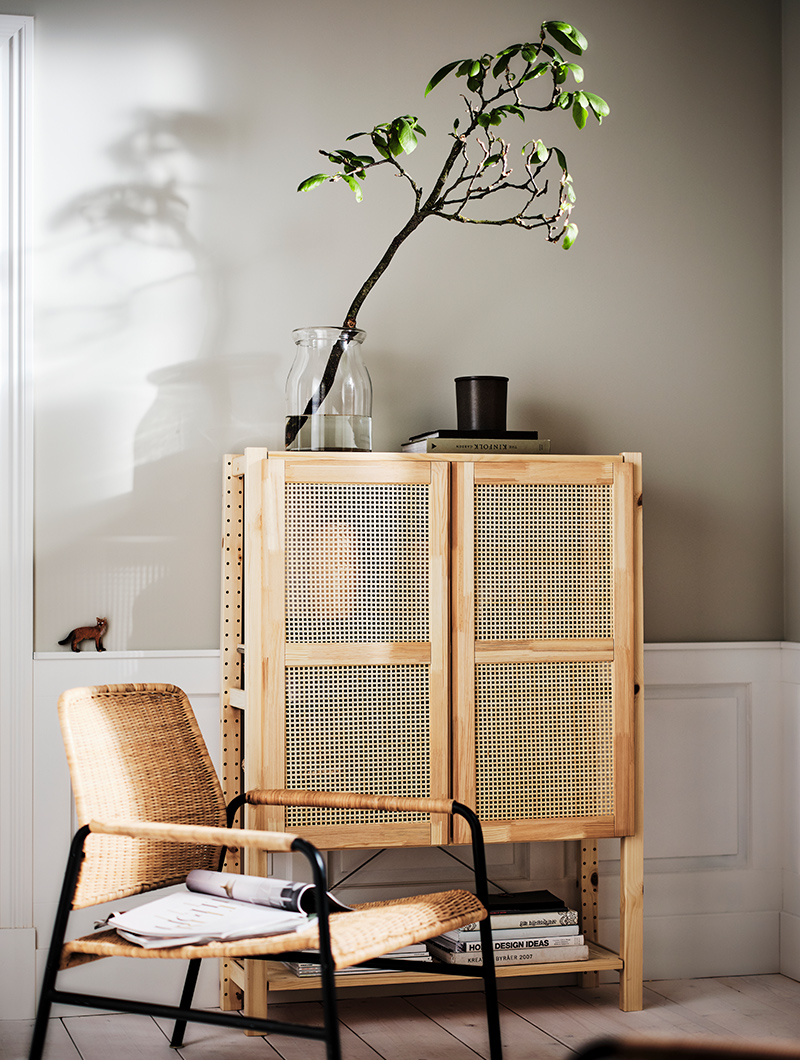 A shelving unit with IVAR doors featuring a BEGARLIG vase on top, and in front, an ULRIKSBERG armchair.