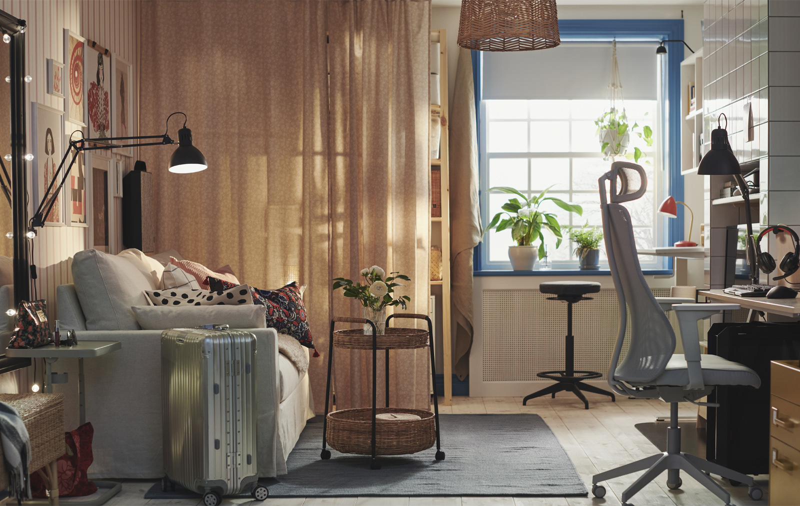 Multifunctional space with sofa, ergonomic chair workspace, blue-framed window, and sheer curtains. Warm ambiance.