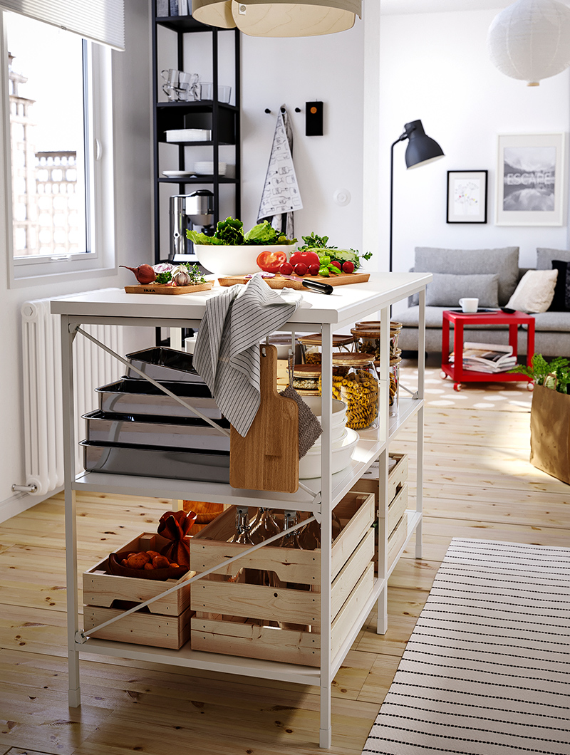 Isla de cocina modeerna con marco de metal blanco con grandes ollas y sartenes debajo