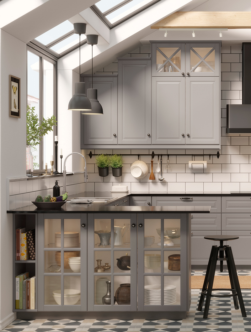 Cocina en colores gris claro, tradicional, hay una isla de cocina con puertas de cristal debajo, hay un taburete alto negro.