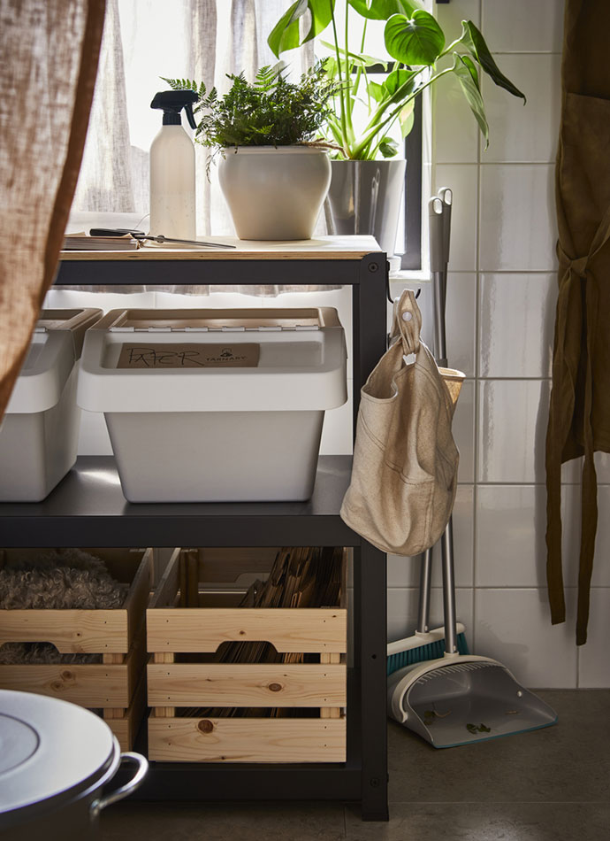 Un carrito utilitario BROR lleno con un contenedor de reciclaje SORTERA, cajas KNAGGLIG con macetas AMBRARÖNN encima, junto a recogedores PEPPRIG.