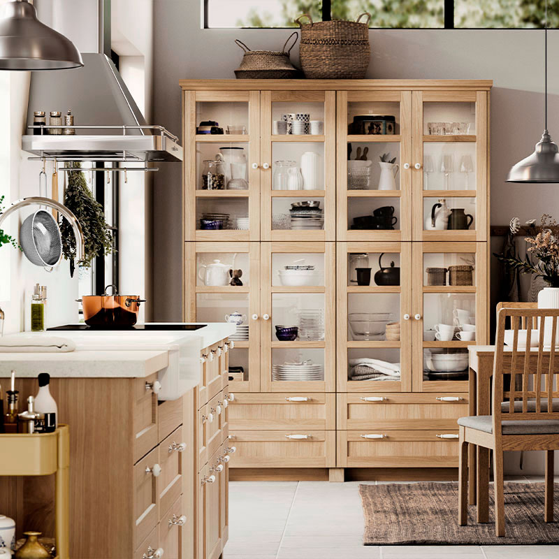 Cocina acogedora con gabinetes de madera, isla y vitrina con vajilla.