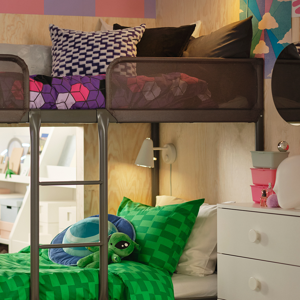 Literas modernas con ropa de cama verde y púrpura, y una pared de madera clara. Un ambiente divertido y juvenil en un dormitorio compartido.