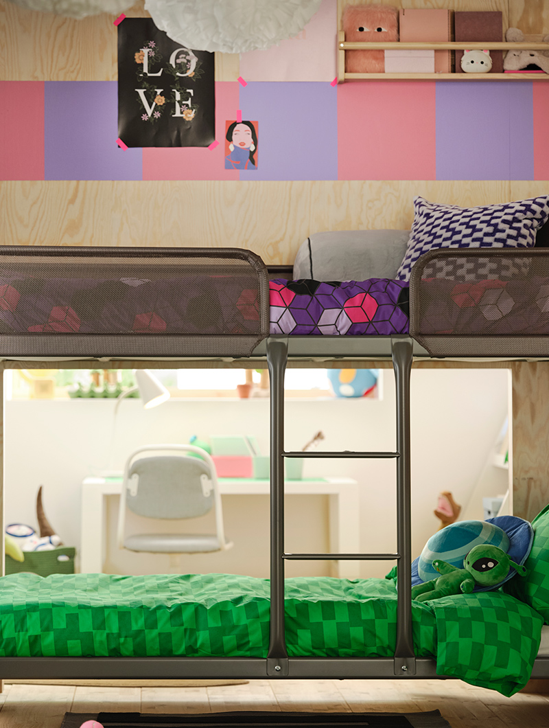 Litera metálica en un dormitorio juvenil, con ropa de cama verde y morada. La pared de madera clara tiene un patrón rosa y lila.