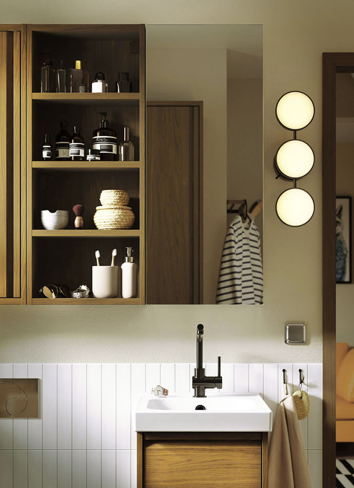 Baño moderno con espejo, estantes de madera con artículos de tocador, lavabo blanco y apliques de pared circulares.