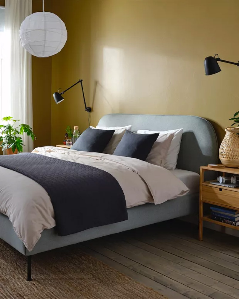 Una cama cubierta por juego de sábana y almohada ULLVIDE junto a mesita de noche NORDKISA
