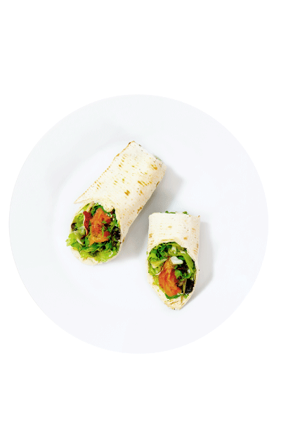 Dos trozos de un wrap de tortilla tostada servidos en un plato redondo blanco, rellenos de ensalada verde brillante y trozos de salmón ahumado.
