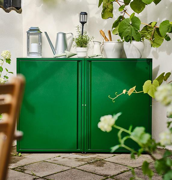 Mueble de exterior verde con varios artículos, como regaderas, jarras y macetas.