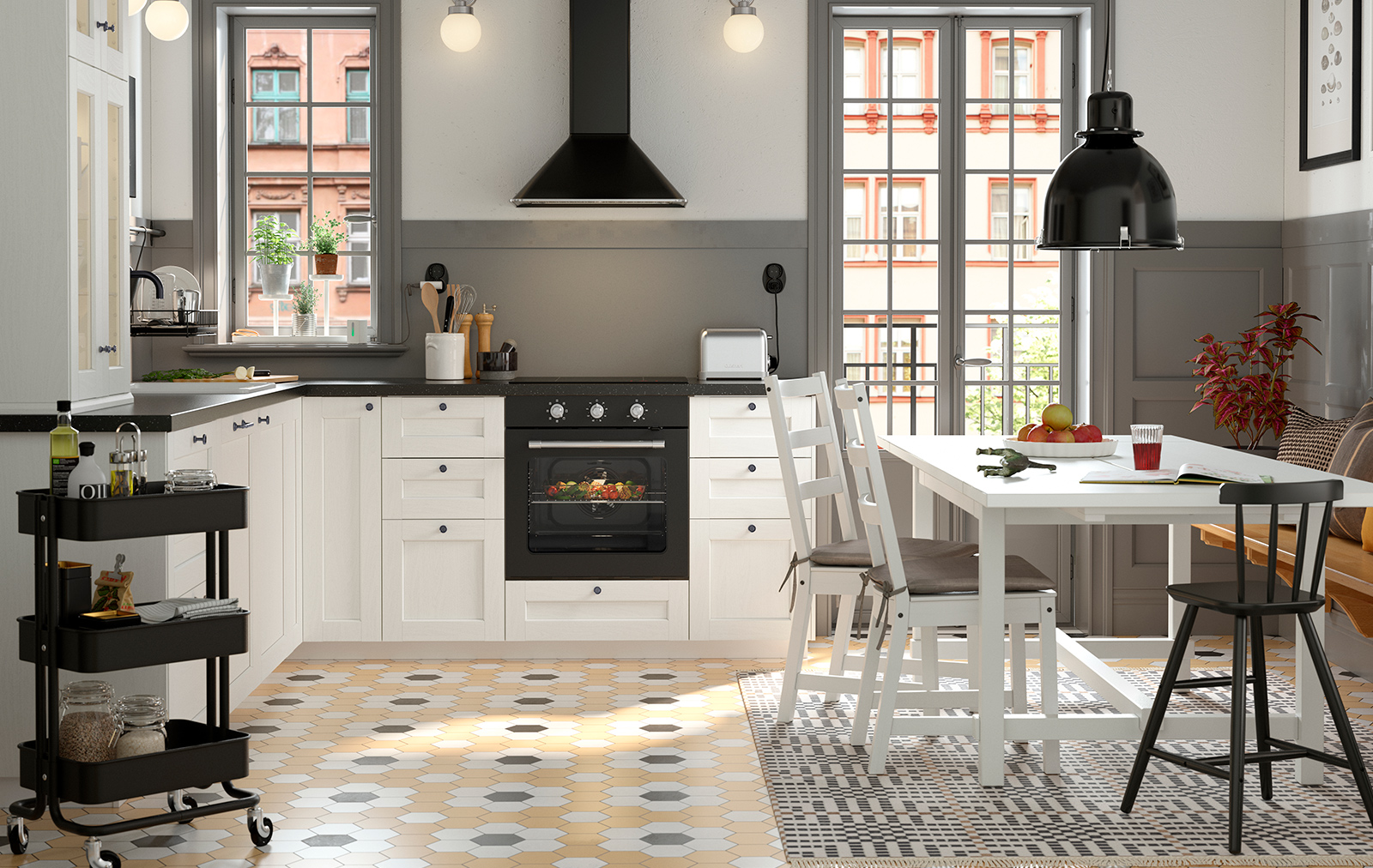 Cocina moderna y luminosa con gabinetes blancos, detalles en negro y un acogedor comedor. El suelo combina patrones para dar dinamismo al ambiente.