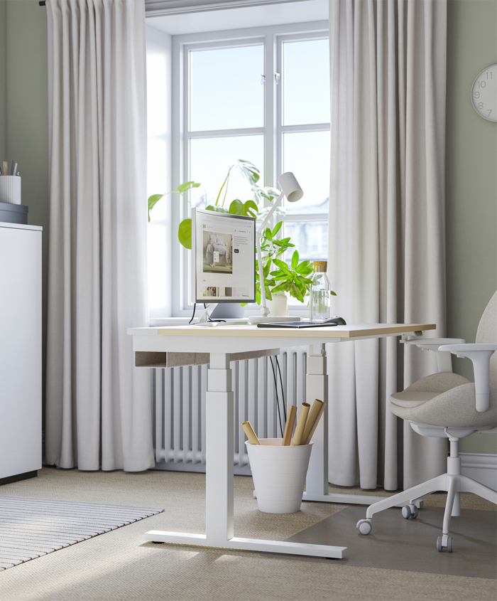 Office space with modern desk and work chair on top of a modern computer in front of a large window with thick white curtains