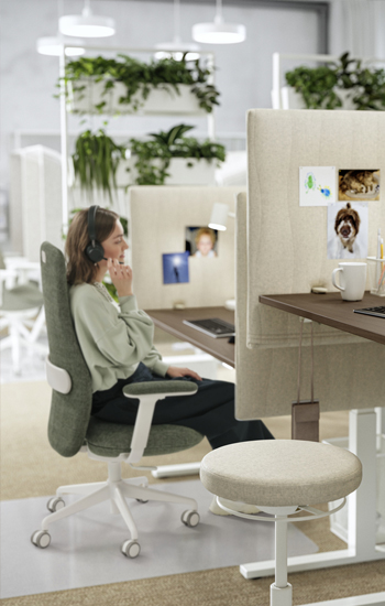 Creative office, with comfortable work chair and cubicles that separate one desk from the other, there is a person on a video call.