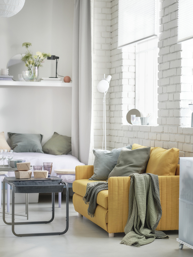 Studio apartment with bed and sofa, featuring a BLÅSER mirror and a RÄFFELBJÖRK vase.