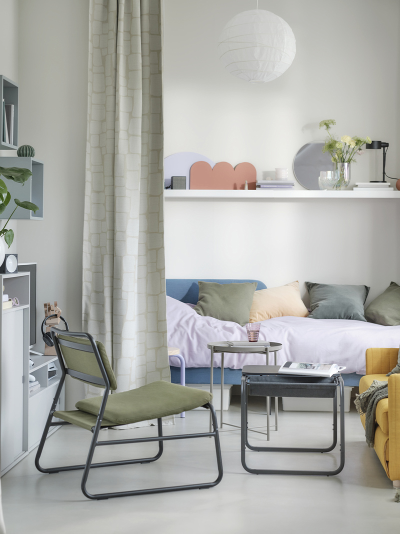 Studio apartment with green armchairs, a GLADOM side table, EKET shelving unit, and SPIKSMED cabinet. Also featuring a BLÅSER mirror and a RÄFFELBJÖRK vase.