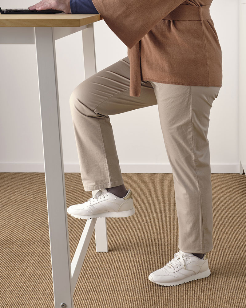 Bottom view of a high desk and male legs in front of one in climbing position on a tabletop support