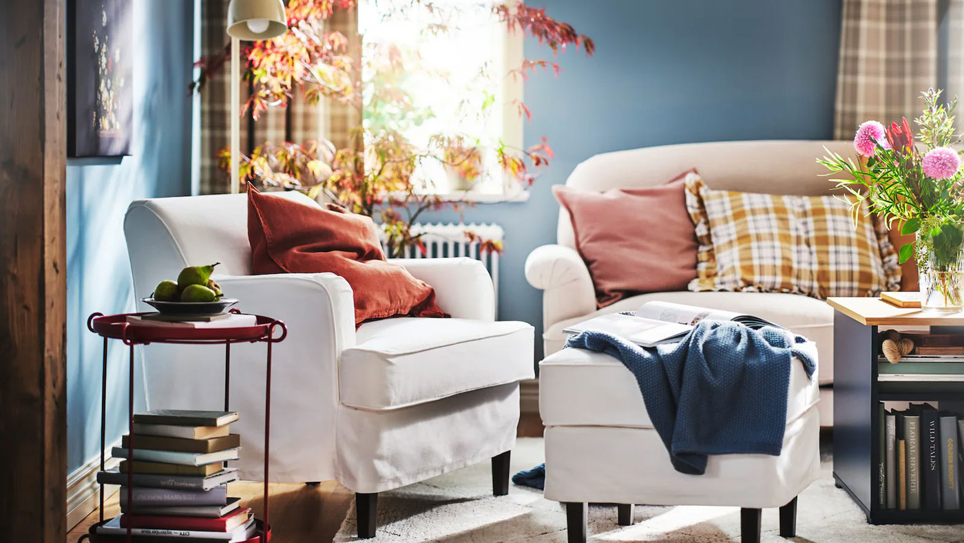Rincón de lectura de estilo tradicional con un cómodo sillón, cojines y mantas, velas y flores para crear un ambiente relajante.