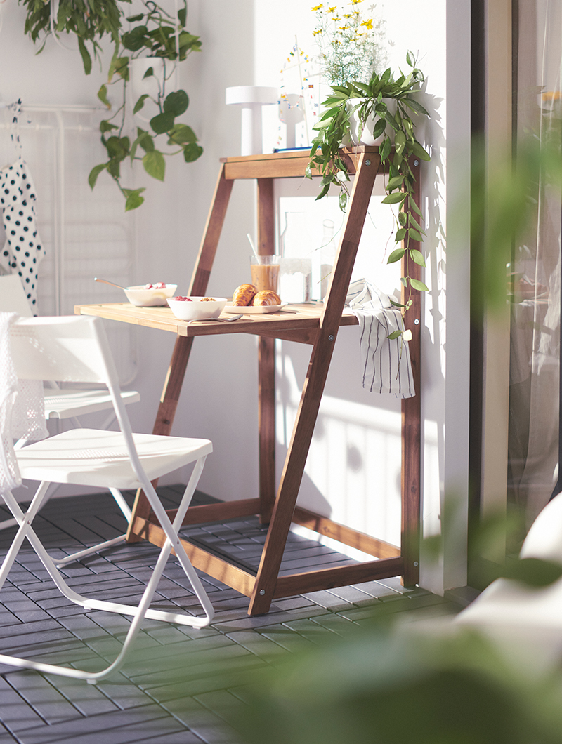 White outdoor chair, with a desk type outdoor table, on a balcony.