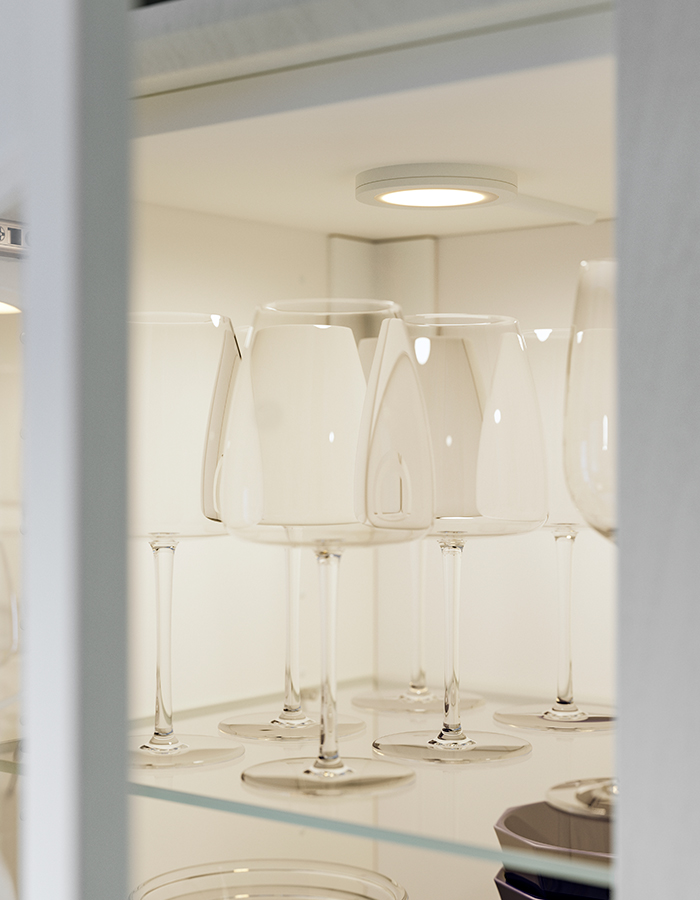 Gabinete con puerta de madera y vidrio, que contiene una copa de vino DYRGRIP, iluminado por una luz LED MITTLED.