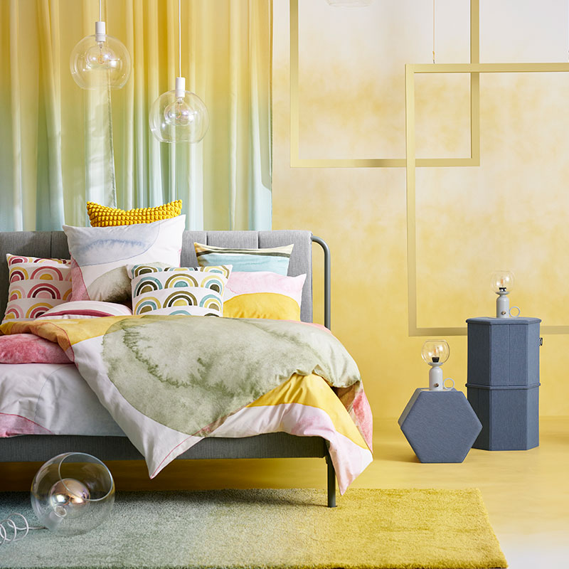 Colorido y artístico dormitorio moderno, una cama llena de cojines y edredones de diferentes colores.
