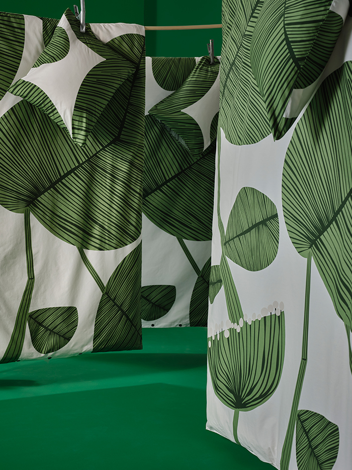 Cortinas blancas con grandes hojas verdes estampadas, en un entorno de fondo verde