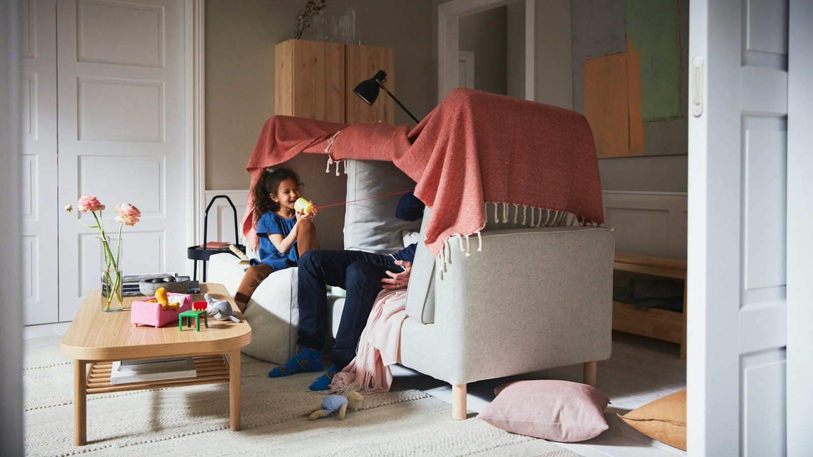 Una niña jugando con su padre en el sofá del salón de su casa