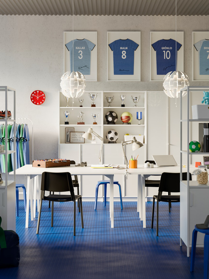 Sala de estudio y creatividad para niños, hay estanterías modernas con libros, hay pupitres con ordenadores y al fondo estanterías con trofeos deportivos y balones y camisetas de fútbol enmarcados.