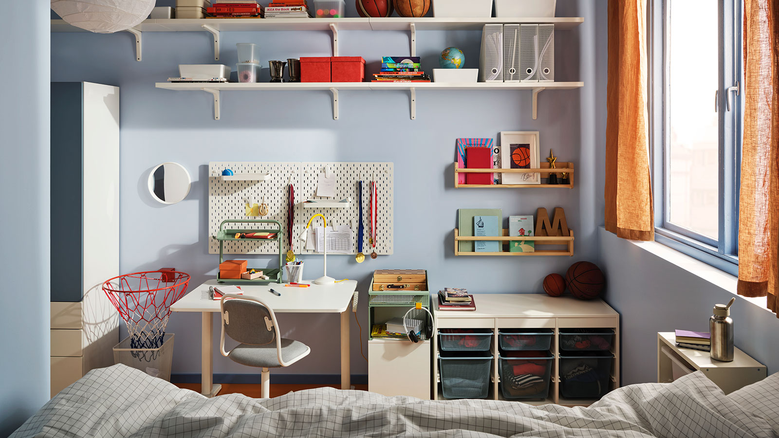 Organized kids' room with desk, shelves, storage bins, and sports decor by the window.