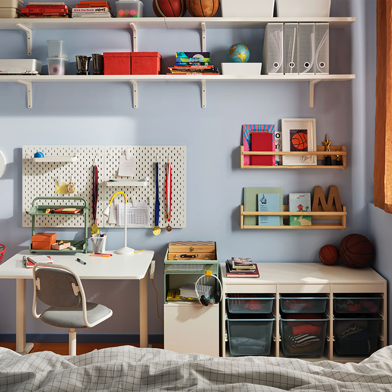 Organized kids' room with desk, shelves, storage bins, and sports decor by the window.